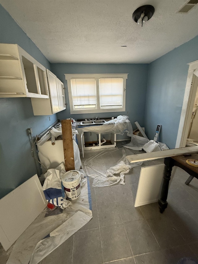 miscellaneous room featuring dark tile patterned flooring and a textured ceiling