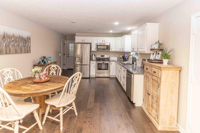 kitchen featuring sink, dark wood-type flooring, stone counters, white cabinetry, and appliances with stainless steel finishes