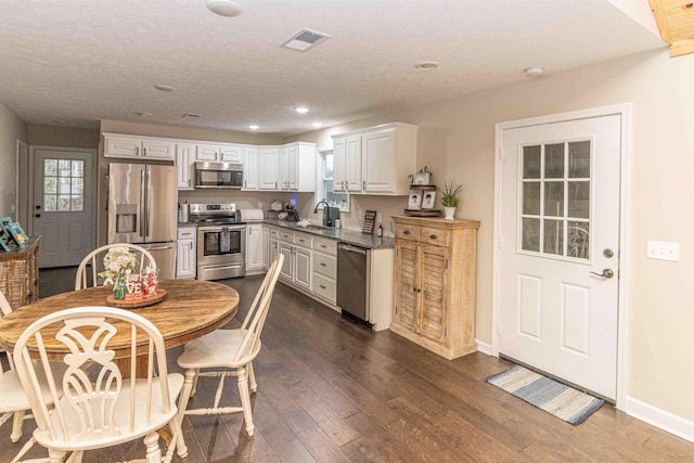 kitchen with sink, white cabinets, stainless steel appliances, dark wood-type flooring, and a textured ceiling