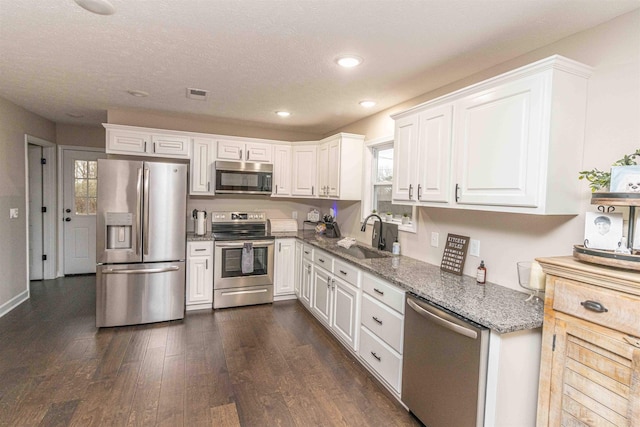 kitchen featuring sink, white cabinetry, dark stone countertops, appliances with stainless steel finishes, and dark hardwood / wood-style floors