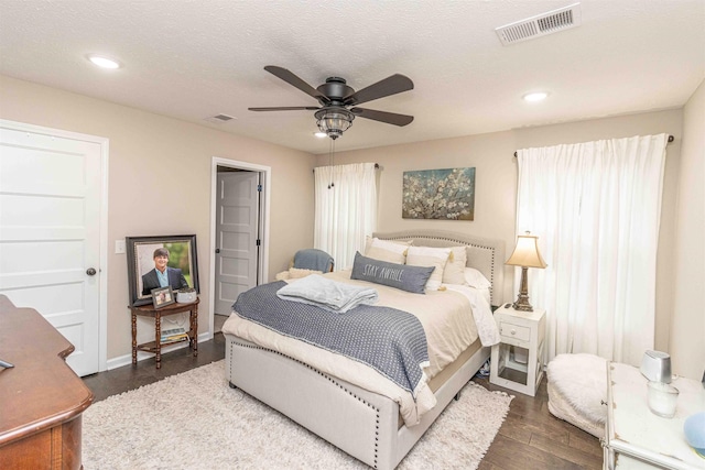 bedroom with a textured ceiling, dark hardwood / wood-style floors, and ceiling fan