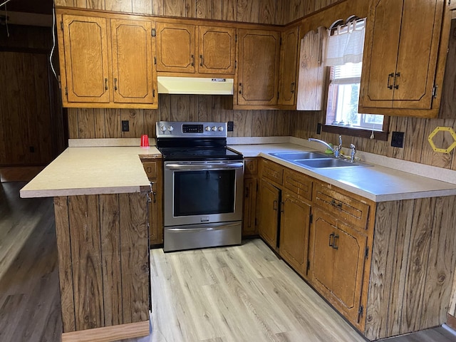 kitchen featuring sink, wooden walls, light wood-type flooring, and electric stove