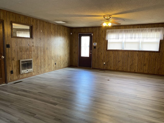 unfurnished living room featuring ceiling fan, a textured ceiling, heating unit, and light hardwood / wood-style flooring