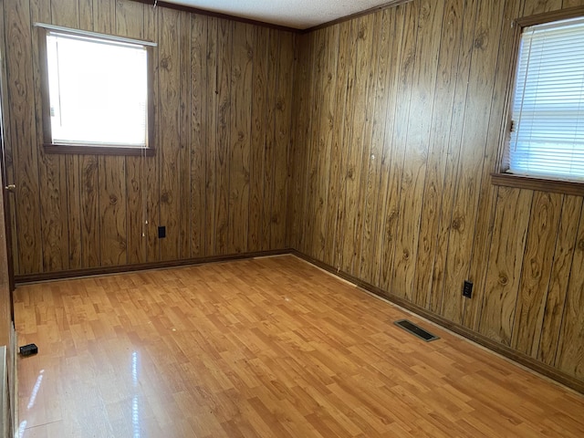 unfurnished room featuring light hardwood / wood-style flooring, ornamental molding, and wood walls