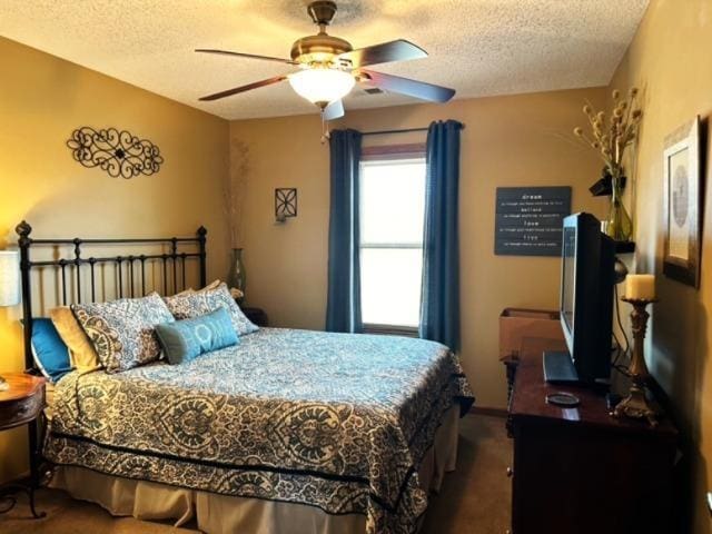 bedroom with ceiling fan, dark carpet, and a textured ceiling