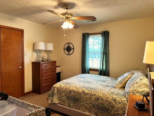 carpeted bedroom featuring ceiling fan and a textured ceiling