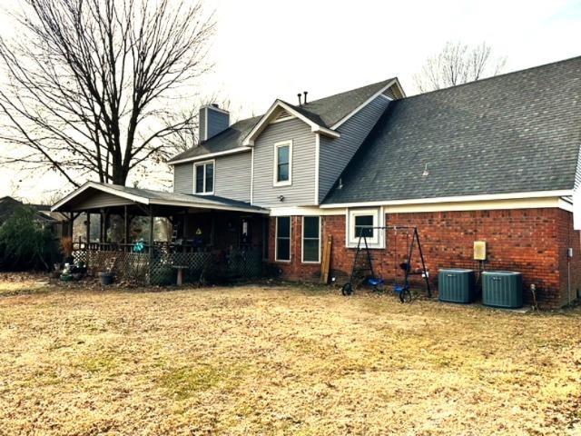 back of property with a lawn and central air condition unit