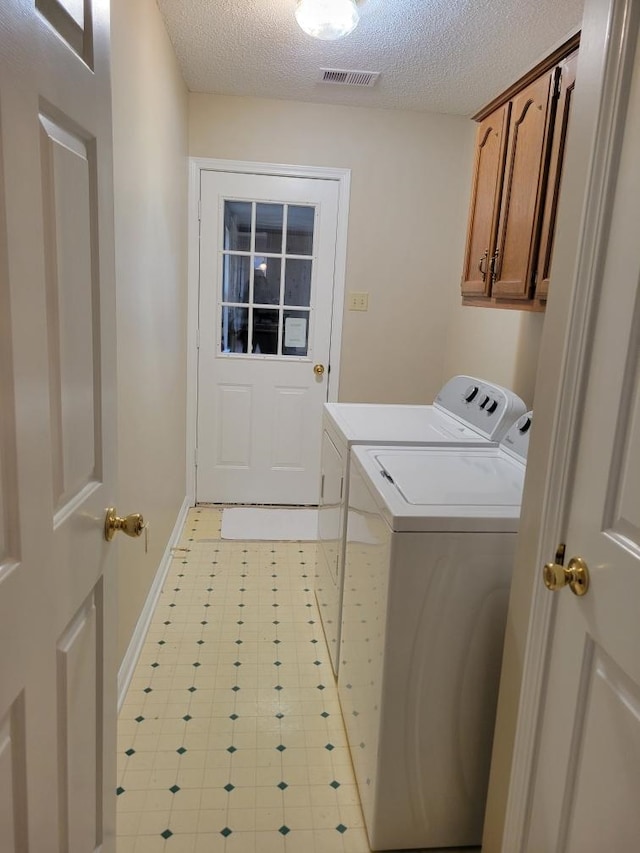 laundry area featuring cabinets, independent washer and dryer, and a textured ceiling