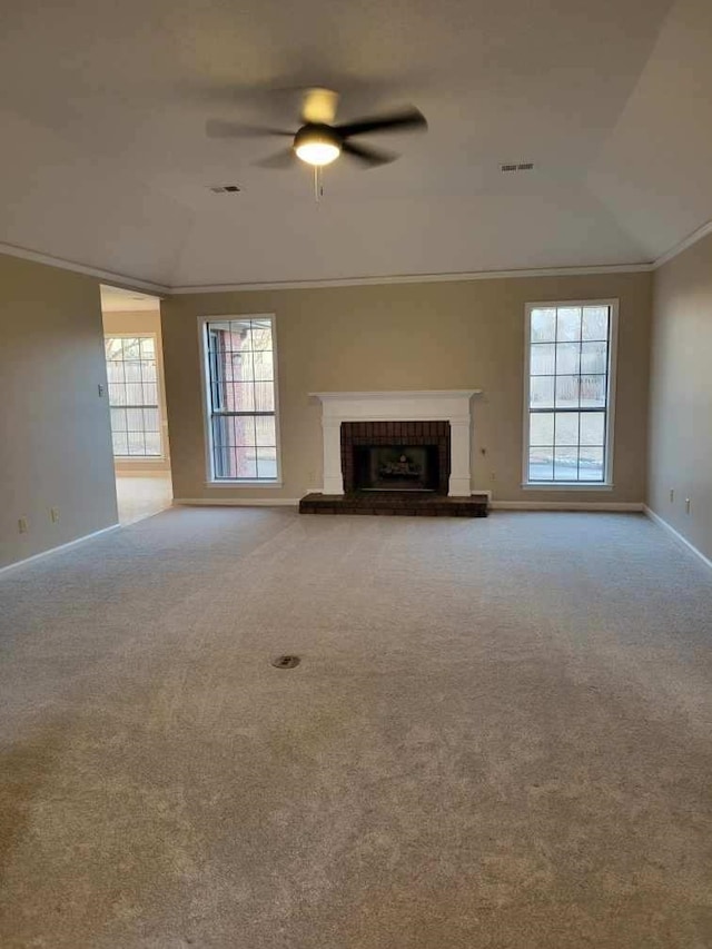 unfurnished living room with carpet floors, a brick fireplace, a wealth of natural light, and ornamental molding