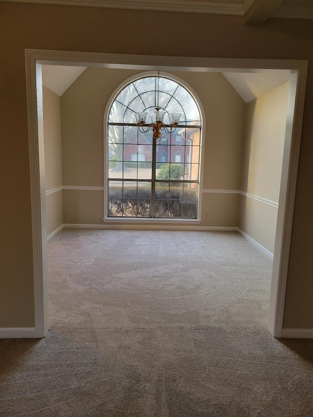 carpeted empty room featuring vaulted ceiling and an inviting chandelier