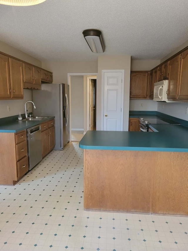 kitchen featuring sink, stainless steel appliances, kitchen peninsula, and a textured ceiling