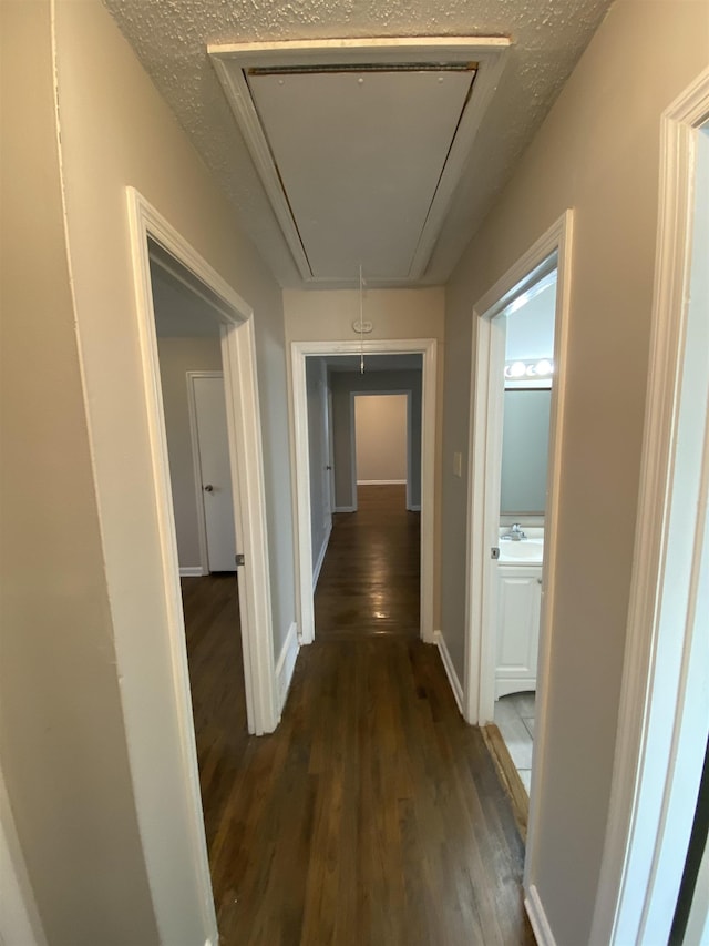 corridor with sink, a textured ceiling, and dark hardwood / wood-style flooring