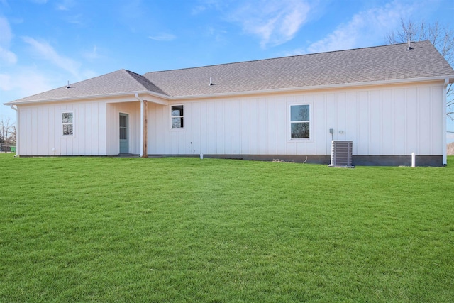 rear view of house with cooling unit and a yard