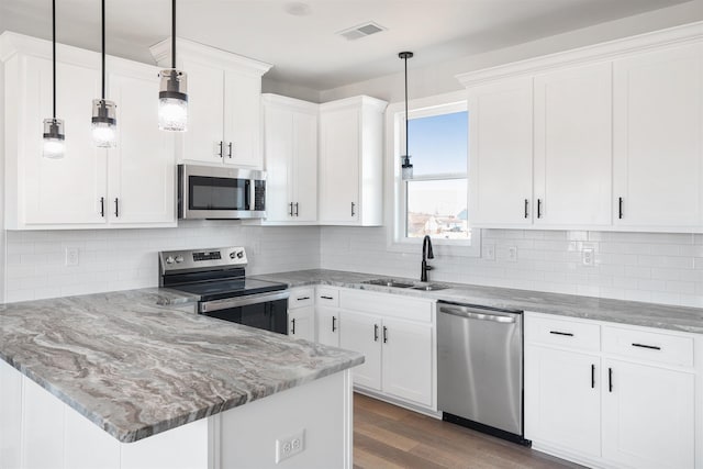 kitchen with sink, decorative light fixtures, white cabinets, and appliances with stainless steel finishes