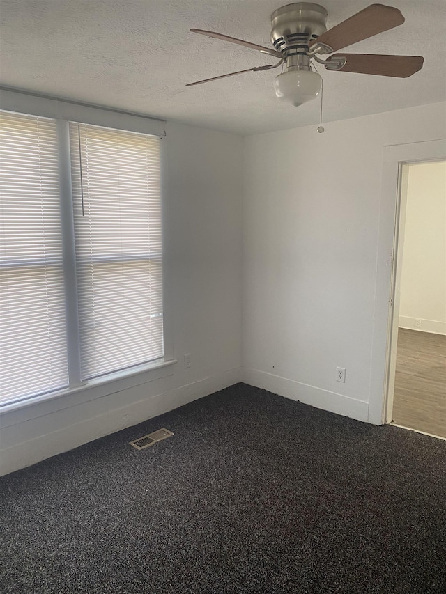 carpeted spare room with ceiling fan and a textured ceiling