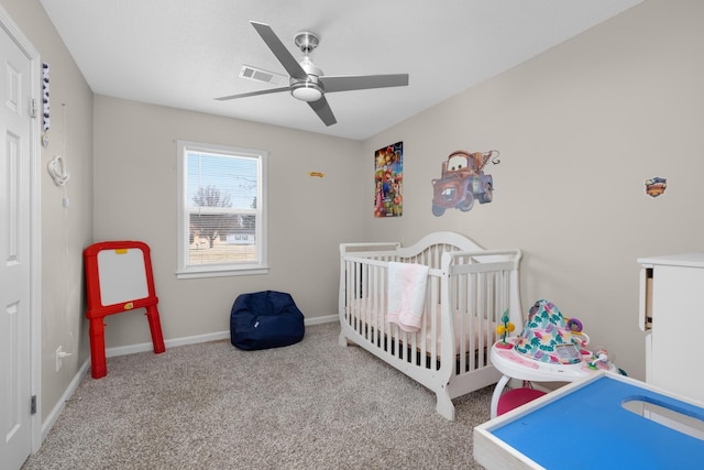 carpeted bedroom featuring a nursery area and ceiling fan