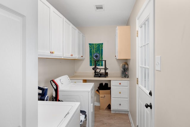 clothes washing area featuring cabinets, separate washer and dryer, and light hardwood / wood-style flooring