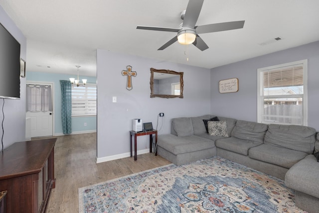 living room with ceiling fan with notable chandelier and light wood-type flooring