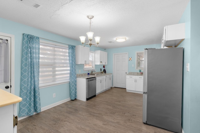 kitchen with stainless steel appliances, sink, white cabinets, and light hardwood / wood-style floors