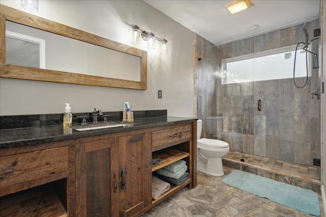 bathroom with vanity, a shower with door, and toilet