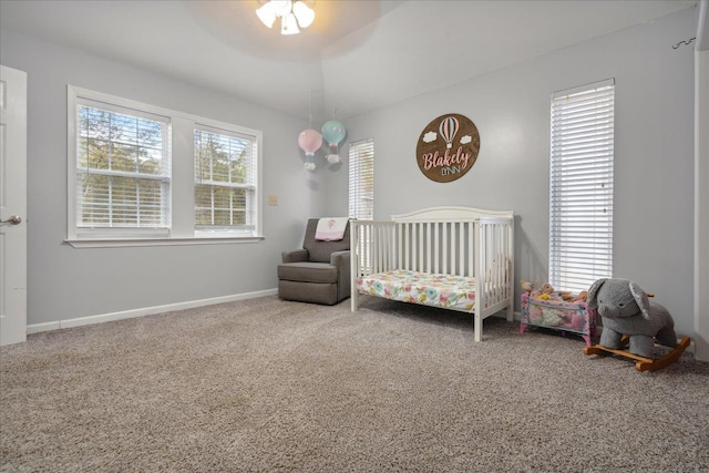 carpeted bedroom with ceiling fan and a crib