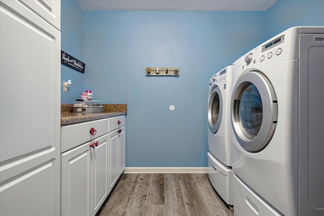 laundry room featuring cabinets, separate washer and dryer, and light hardwood / wood-style floors