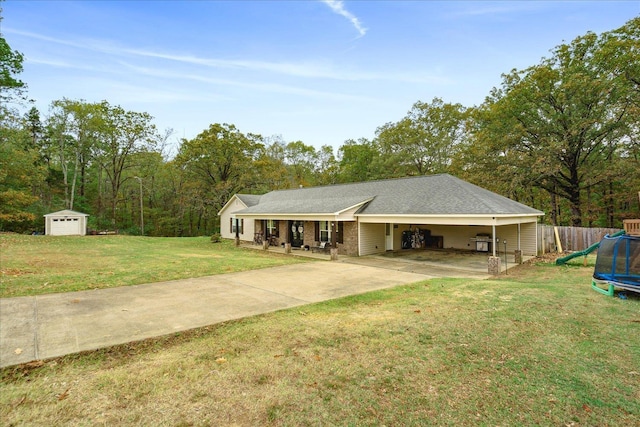 single story home with a carport, a storage unit, a front lawn, and a trampoline