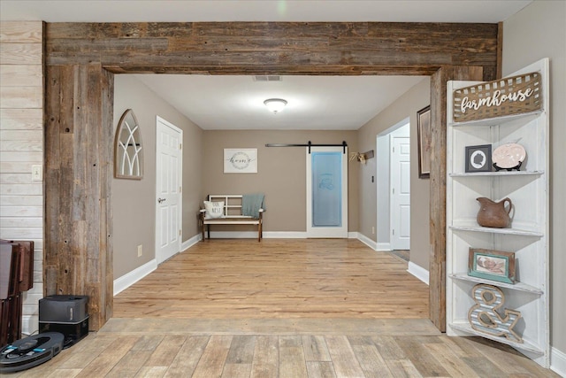 hallway with hardwood / wood-style floors, a barn door, and wood walls