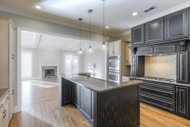 kitchen featuring dark stone countertops, cream cabinets, a kitchen island, and appliances with stainless steel finishes