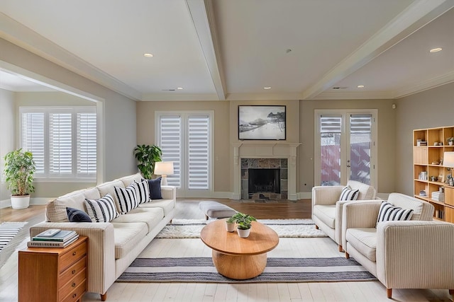 living room with crown molding, a fireplace, beam ceiling, and light hardwood / wood-style flooring