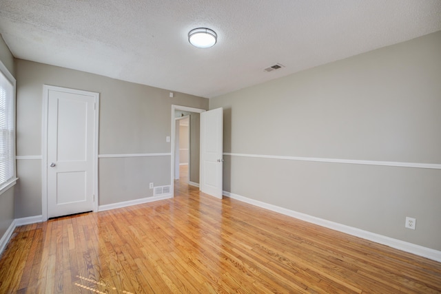 spare room with light hardwood / wood-style flooring and a textured ceiling