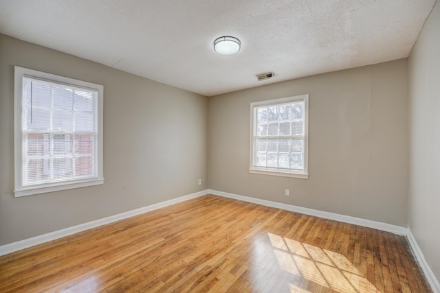 unfurnished room with a textured ceiling and light wood-type flooring