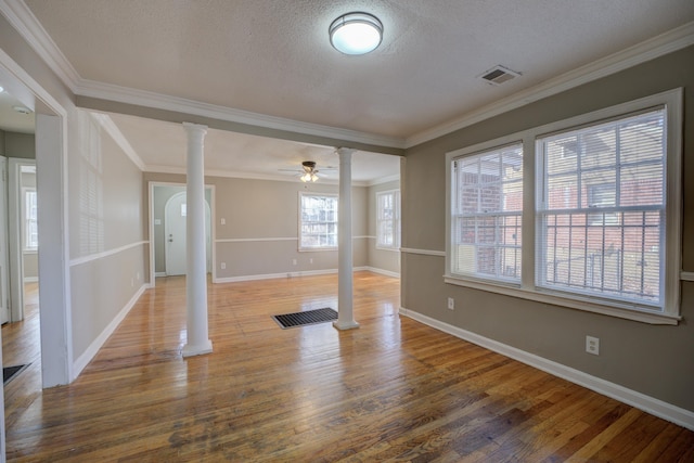 workout room featuring crown molding, wood-type flooring, a textured ceiling, and ornate columns