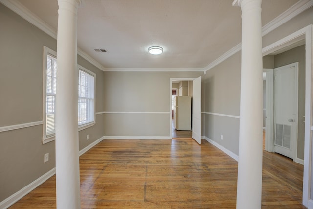 empty room with ornate columns, crown molding, and hardwood / wood-style flooring