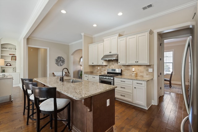 kitchen featuring sink, appliances with stainless steel finishes, light stone countertops, an island with sink, and white cabinets