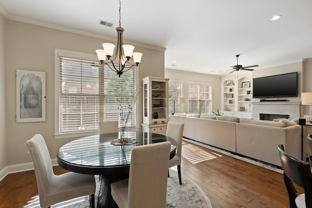 dining area featuring ornamental molding, ceiling fan with notable chandelier, dark hardwood / wood-style flooring, and built in shelves