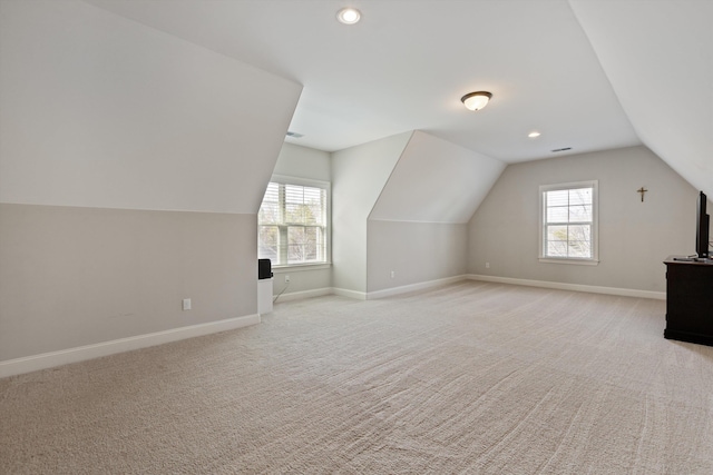 additional living space featuring lofted ceiling, plenty of natural light, and light carpet