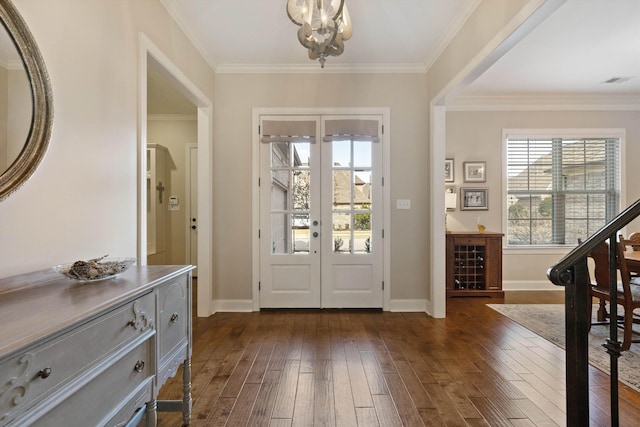 foyer with a notable chandelier, dark wood-type flooring, ornamental molding, and french doors