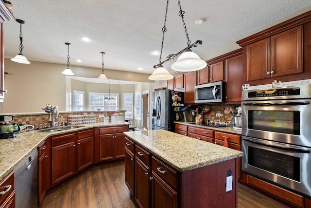 kitchen featuring sink, hanging light fixtures, dark hardwood / wood-style flooring, a kitchen island, and stainless steel appliances