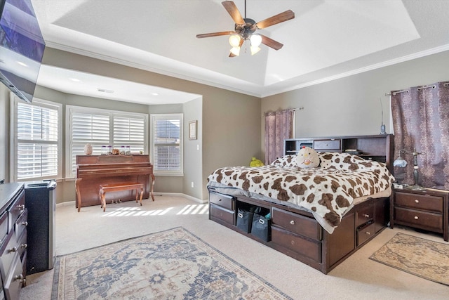 carpeted bedroom with ceiling fan, ornamental molding, and a raised ceiling