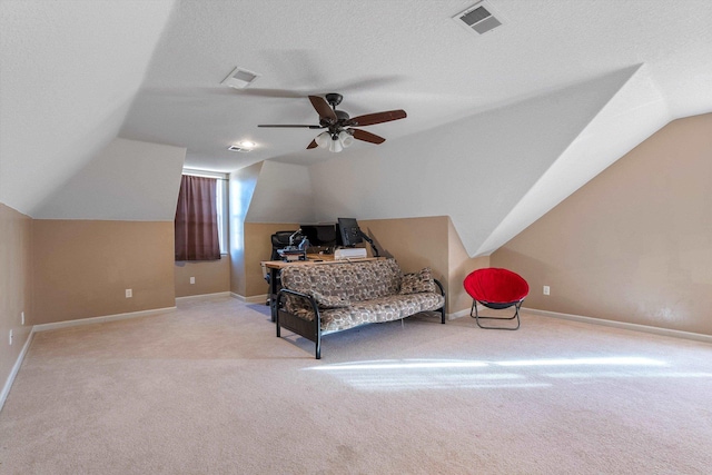 living area featuring ceiling fan, lofted ceiling, light colored carpet, and a textured ceiling