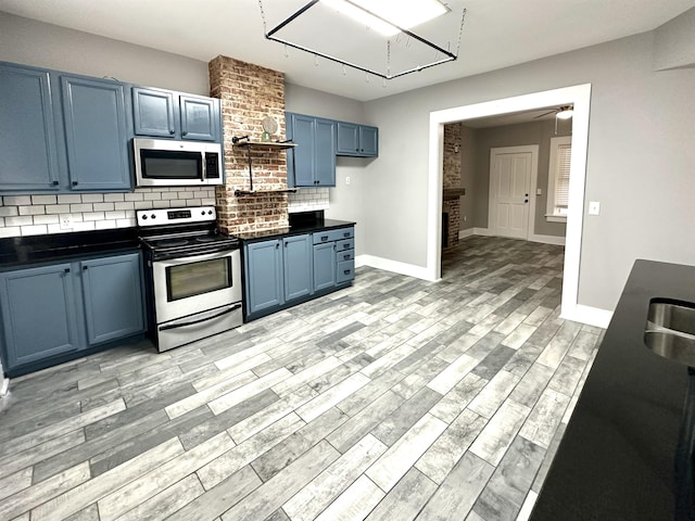 kitchen featuring blue cabinetry, appliances with stainless steel finishes, ceiling fan, light hardwood / wood-style floors, and decorative backsplash