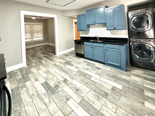 kitchen featuring stacked washer / dryer, dishwasher, sink, and blue cabinetry