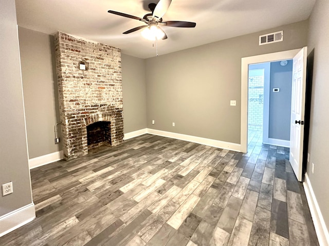 unfurnished living room featuring ceiling fan, a brick fireplace, and dark hardwood / wood-style flooring