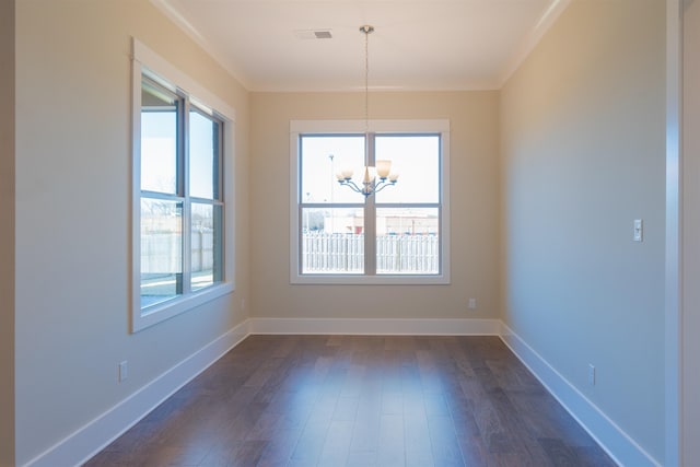 unfurnished dining area featuring an inviting chandelier, crown molding, dark wood-type flooring, and a healthy amount of sunlight