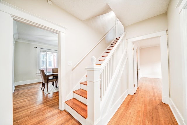 staircase featuring crown molding and wood-type flooring