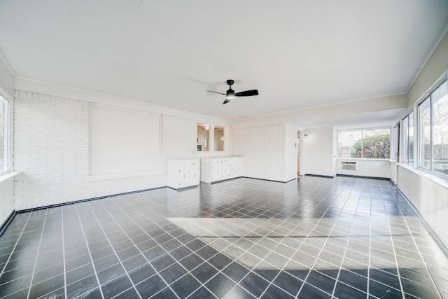 interior space featuring ceiling fan and brick wall