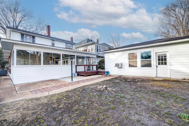 rear view of house with a wall unit AC, a sunroom, a patio, and central air condition unit