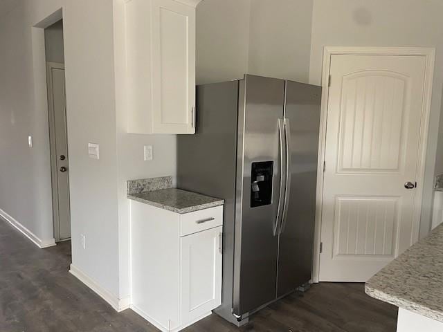 kitchen with white cabinetry, dark wood-type flooring, light stone countertops, and stainless steel refrigerator with ice dispenser