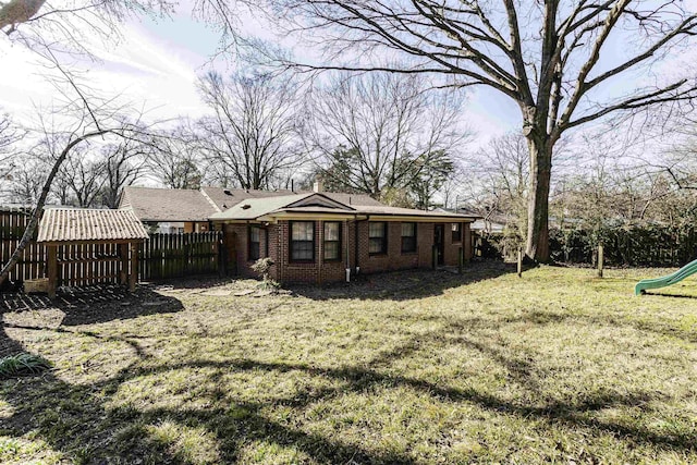 rear view of property with a yard and a playground